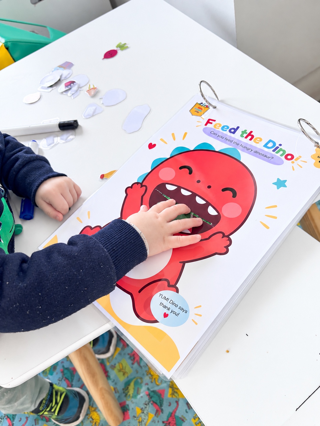 A toddler feeding a piece into the dinosaur activity